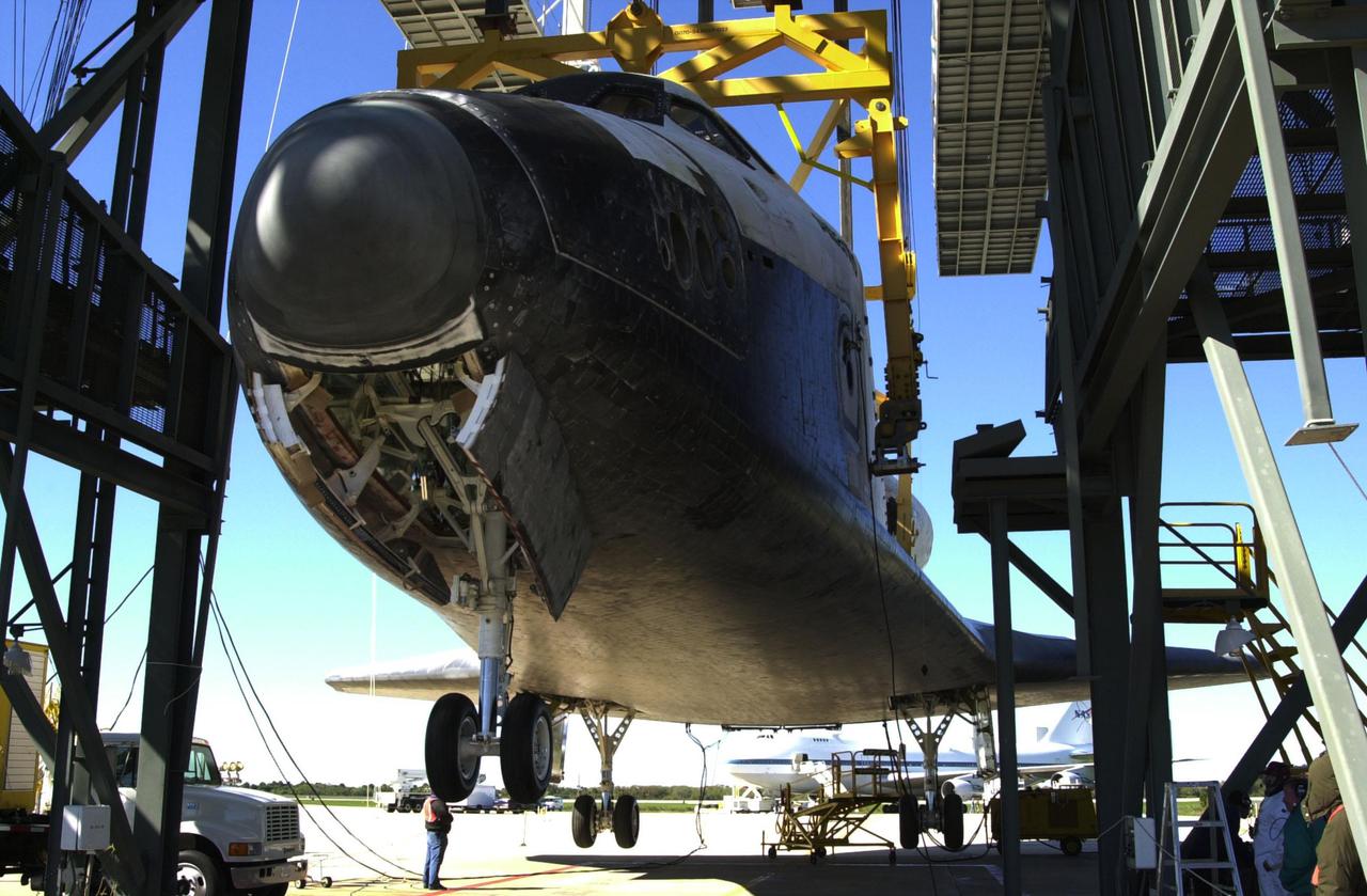 KENNEDY SPACE CENTER, FLA. -- Wheels are lowered on the orbiter Atlantis as it hangs suspended by an overhead crane in the mate_demate device at KSC’s Shuttle Landing Facility. Atlantis was removed from the back of the Shuttle Carrier Aircraft in the background. Atlantis just returned from California atop the SCA after its Feb. 19 landing at Edwards Air Force Base concluding mission STS-98. The ferry flight began March 1; unfavorable weather conditions kept it on the ground at Altus AFB, Okla., until it could return to Florida. Atlantis will be transported to the Orbiter Processing Facility to prepare it for mission STS-104, the 10th construction flight to the International Space Station, scheduled to launch June 8