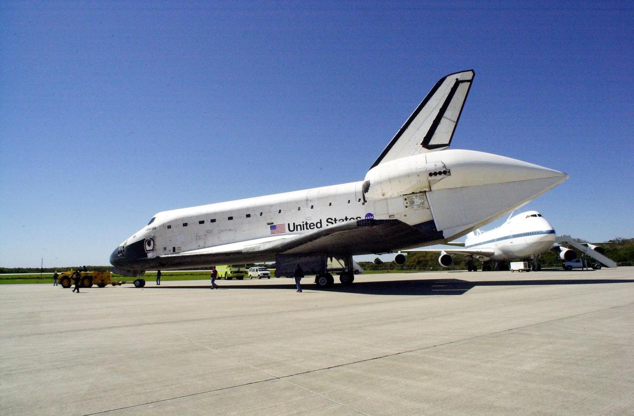 KENNEDY SPACE CENTER, FLA. -- At the Shuttle Landing Facility, orbiter Atlantis is towed from the mate_demate device to the Orbiter Processing Facility. A tail cone covers its aft engines. In the background is the Shuttle Carrier Aircraft, a modified Boeing 747, that carried it piggyback known as a ferry flight from California. Atlantis landed Feb. 19 at Edwards Air Force Base concluding mission STS-98. The ferry flight back to KSC began March 1; unfavorable weather conditions kept it on the ground at Altus AFB, Okla., until it could return to Florida March 5. Atlantis will be prepared in the OPF for mission STS-104, the 10th construction flight to the International Space Station, scheduled to launch June 8