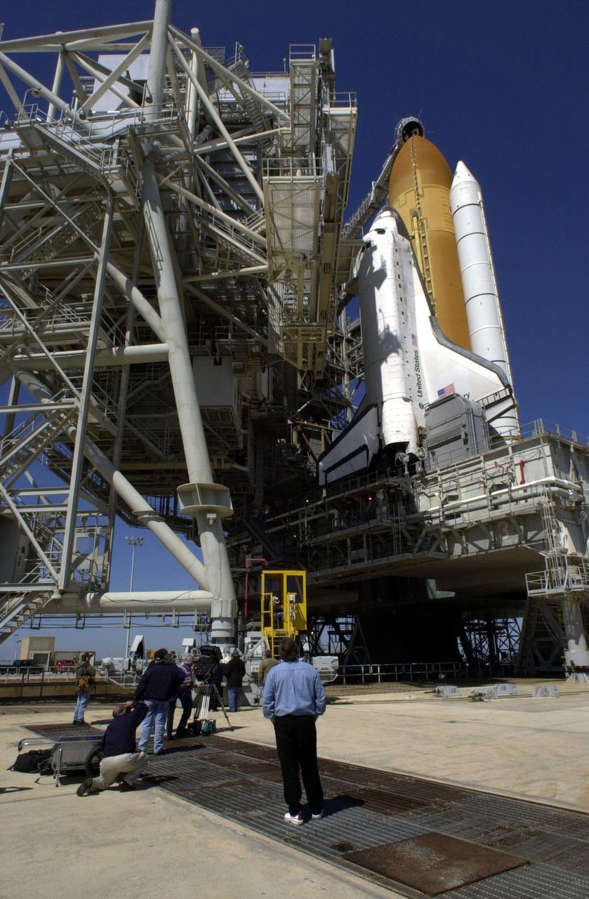 KENNEDY SPACE CENTER, Fla. -- Less than 24 hours before launch of STS-102, photographers capture the rollback of the Rotating Service Structure from around Space Shuttle Discovery on Launch Pad 39B. Poised above the external tank is the Gaseous Oxygen Vent Arm with the “beanie cap,” a vent hood. The RSS provides protected access to the orbiter for changeout and servicing of payloads. It is supported by a rotating bridge that pivots about a vertical axis on the west side of the pad’s flame trench. Space Shuttle Discovery is scheduled to launch March 8 at 6:42 a.m. EST on the eighth construction flight to the International Space Station. It carries the Multi-Purpose Logistics Module Leonardo, the primary delivery system used to resupply and return Station cargo requiring a pressurized environment. Leonardo will deliver up to 10 tons of laboratory racks filled with equipment, experiments and supplies for outfitting the newly installed U.S. Laboratory Destiny