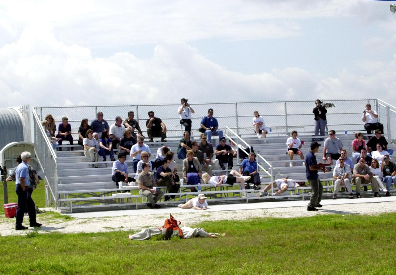 KENNEDY SPACE CENTER, FLA. -- Near the turn basin in the Launch Complex 39 area, employees take part in a staged mass casualty exercise at the KSC employee viewing site. The exercise, simulating a sniper attack (man in black at right), was staged to validate capabilities of KSC’s fire, medical helicopter transport and security personnel to respond to such an event