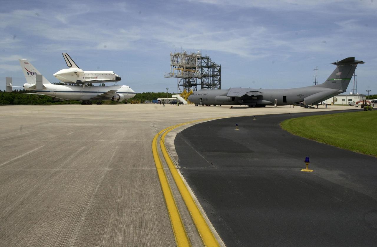 KENNEDY SPACE CENTER, FLA. -- At the Shuttle Landing Facility, orbiter Endeavour and the Shuttle Carrier Aircraft are towed past the Pathfinder, a C-141, that precedes the ferry flight on its journey. The Endeavour_SCA completed a two-day transcontinental ferry flight from Edwards Air Force Base, Calif. . Endeavour landed at Edwards AFB after a 12-day mission, STS-100, to the International Space Station. Endeavour will be demated from the SCA and towed to the Orbiter Processing Facility bay 1 where it will begin processing for mission STS-108