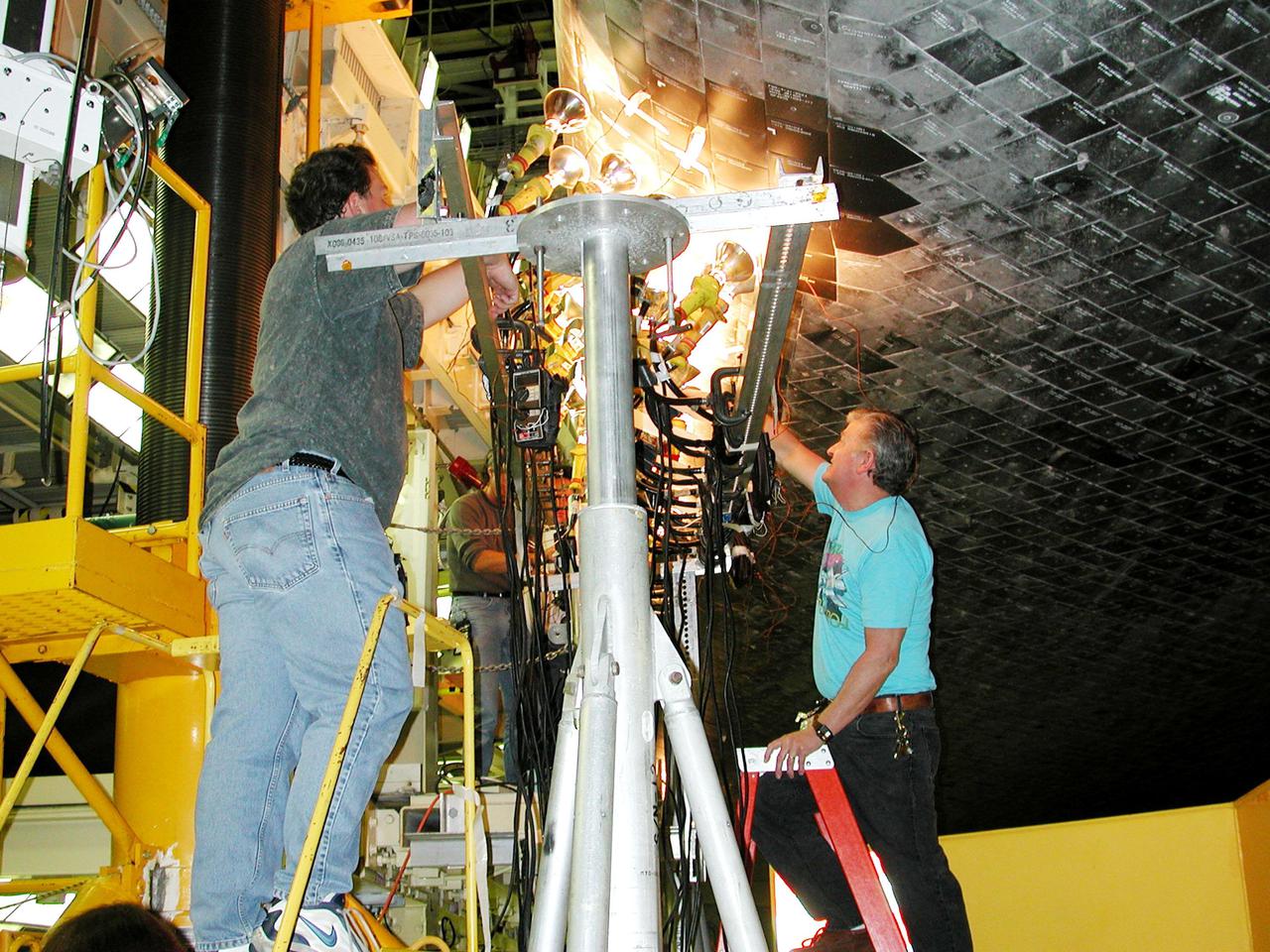 KENNEDY SPACE CENTER, FLA. -- Banks of lights dry tiles on orbiter Atlantis in the Orbiter Processing Facility. Significant rainstorms during the orbiter’s turnaround for a ferry flight home from Edwards Air Force Base, Calif., caused the moisture problem. The tiles are part of the Thermal Protection System used on orbiters for extreme temperatures encountered during landing