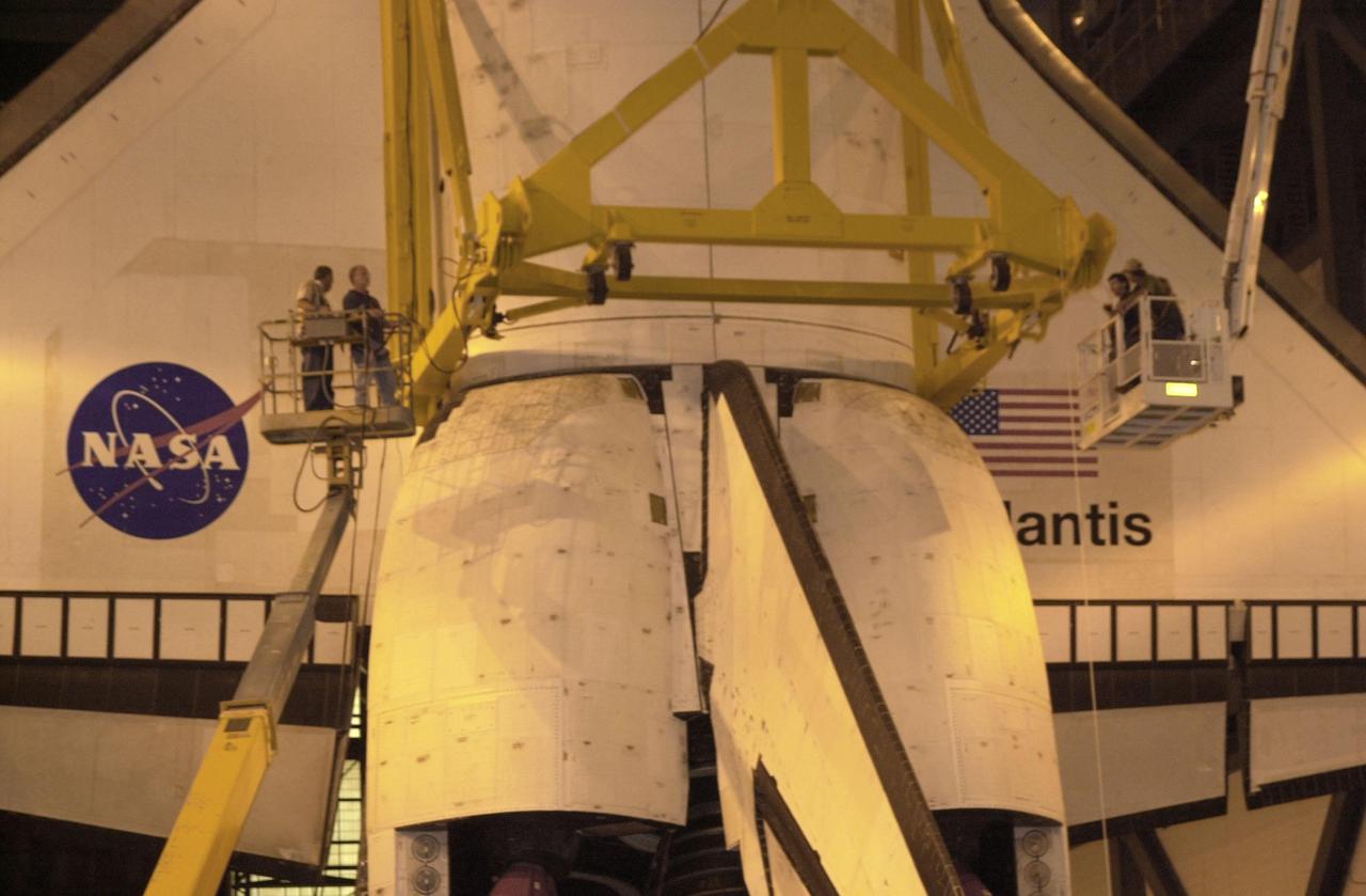 KENNEDY SPACE CENTER, FLA. -- This closeup shows the workers, standing on lifts, who are checking the bolts on the apparatus holding the orbiter Atlantis. The orbiter will be rotated and lifted up and over to a high bay and stacked with its external tank and solid rocket boosters. Space Shuttle Atlantis is scheduled to launch on mission STS-104 in early July