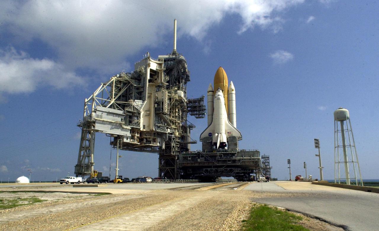 KENNEDY SPACE CENTER, Fla. -- After a journey of more than 8 hours from the Vehicle Assembly Building, Space Shuttle Atlantis sits on Launch Pad 39B. At left is the Rotating Service Structure, which will roll on its axis to enclose the Shuttle until launch. Towering above the Fixed Service Structure next to it is the 80-foot tall lightning mast that provides protection from lightning strikes. On the right is the elevated water tank with a capacity of 300,000 gallons. Part of the Sound Suppression Water System, the water in the tank is released just before ignition of the orbiter’s three main engines and twin solid rocket boosters and flow through parallel 7-foot-diameter pipes to the pad area. The Shuttle is targeted for launch no earlier than July 12 on mission STS-104, the 10th flight to the International Space Station. The payload on the 11-day mission is the Joint Airlock Module, which will allow astronauts and cosmonauts in residence on the Station to perform future spacewalks without the presence of a Space Shuttle. The module, which comprises a crew lock and an equipment lock, will be connected to the starboard (right) side of Node 1 Unity. Atlantis will also carry oxygen and nitrogen storage tanks, vital to operation of the Joint Airlock, on a Spacelab Logistics Double Pallet in the payload bay. The tanks, to be installed on the perimeter of the Joint Module during the mission’s spacewalks, will support future spacewalk operations and experiments plus augment the resupply system for the Station’s Service Module