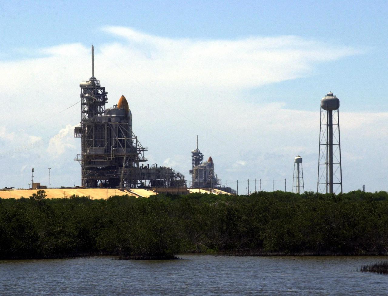 KENNEDY SPACE CENTER, Fla. -- Launch Pads 39A (foreground) and 39B are both seen in this photo, each with a Shuttle in place. Pad 39A holds Space Shuttle Discovery, which rolled out July 2 to be prepared for launch on mission STS-105 in August. Pad 39B holds Space Shuttle Atlantis, which is scheduled to launch Thursday, July 12, on mission STS-104. At right are the 290-foot water tanks that provide 300,000 gallons of water during liftoff. They are part of the sound suppression water system at each pad
