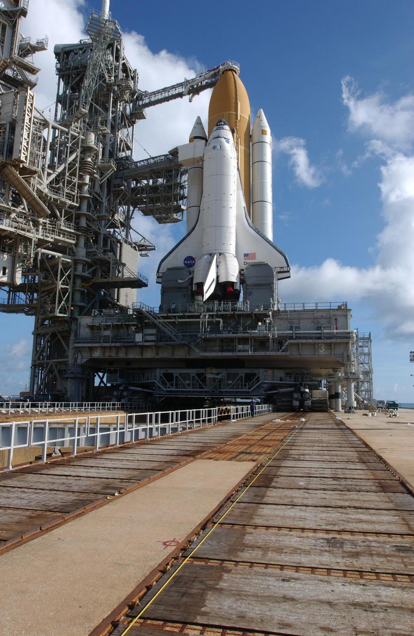 KENNEDY SPACE CENTER, Fla. - With the cloud-spotted blue sky as a backdrop, Space Shuttle Discovery stands ready to undergo launch preparations for mission STS-105. At the bottom of the photo is seen the crawler track on the mound. The crawler-transporter that moved the Shuttle from the Vehicle Assembly Building is beginning to back out from under the mobile launcher platform. Discovery is scheduled to launch in early August on mission STS-105.   Photo by Scott Andrews using a Nikon D1X camera