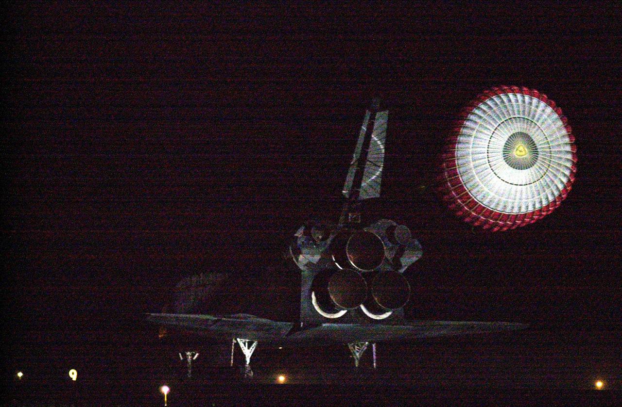 KENNEDY SPACE CENTER, Fla. -- With the drag chute reflected in the bright lights at the Shuttle Landing Facility, Atlantis prepares to land on Runway 15 at the Shuttle Landing Facility to complete a 12-day, 18-hour, 34-minute-long STS-104 mission. Main gear touchdown occurred at 11:38:55 p.m. EDT. At the controls is Commander Steven W. Lindsey. Other crew members on board are Pilot Charles Hobaugh and Mission Specialists Michael Gernhardt, Janet Lynn Kavandi and James F. Reilly. This is the 18th nighttime landing for a Space Shuttle, the 13th at Kennedy Space Center. The mission delivered the Joint Airlock Module to the International Space Station, completing the second phase of the assembly of the Space Station