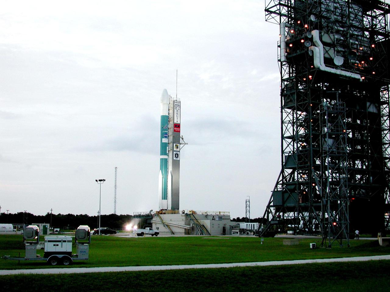 KENNEDY SPACE CENTER, Fla. -- After rollback of the Mobile Service Tower (right), the Delta II rocket with the Genesis spacecraft on top sits on Launch Complex 17-A, Cape Canaveral Air Force Station, ready for liftoff. Genesis will be on a robotic NASA space mission to collect just 10 to 20 micrograms -- or the weight of a few grains of salt -- of solar wind, invisible charged particles that flow outward from the Sun -- and return them to Earth. This treasured smidgen of the Sun will be preserved in a special laboratory for study by scientists over the next century in search of answers to fundamental questions about the exact composition of our star and the birth of our solar system. The Genesis launch is scheduled for Aug. 1, 2001, from CCAFS