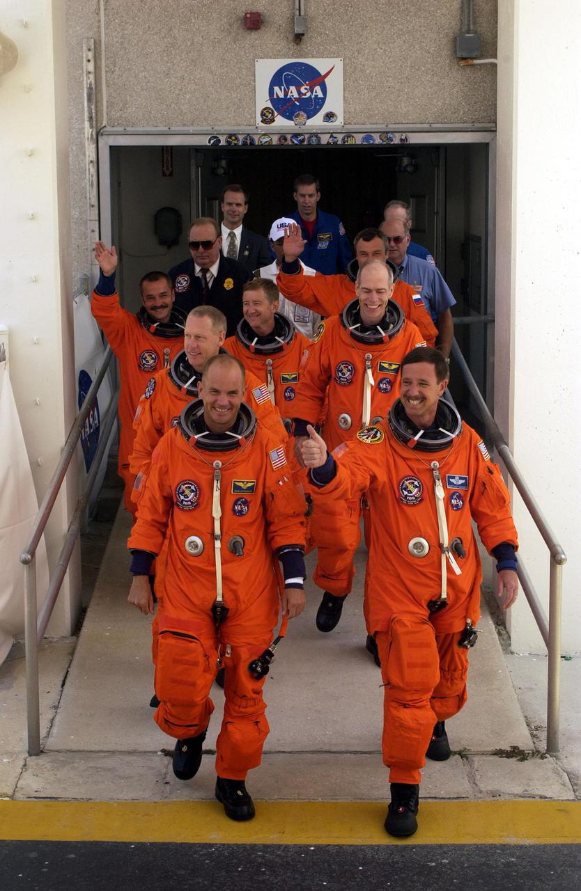 KENNEDY SPACE CENTER, Fla. -- The STS-105 crew exits the Operations and Checkout Building, followed by the Expedition Three (E3) crew. Leading the way are (left to right) Pilot Rick Sturckow and Commander Scott Horowitz; in the second row, Mission Specialists Patrick Forrester and Daniel Barry; in the third row, E3 cosmonaut Mikhail Tyurin, Commander Frank Culbertson, and cosmonaut Vladimir Dezhurov. Forrester and Tyurin are both making their first space flights. On the mission, Discovery will be transporting the Expedition Three crew and several payloads and scientific experiments to the ISS, including the Early Ammonia Servicer (EAS) tank. The EAS, which will support the thermal control subsystems until a permanent system is activated, will be attached to the Station during two spacewalks. The three-member Expedition Two crew will be returning to Earth aboard Discovery after a five-month stay on the Station. Launch is scheduled for 5:38 p.m. EDT Aug. 9. [Photo by Scott Andrews; Nikon D1 camera