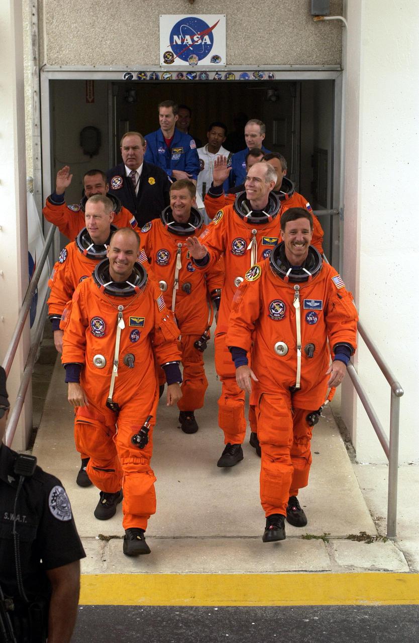 KENNEDY SPACE CENTER, Fla. -- The STS-105 and Expedition Three (E3) crews are smiling as they exit the Operations and Checkout Building on their way to Launch Pad 39A for a second launch attempt. Leading the way are (left to right) Pilot Rick Sturckow and Commander Scott Horowitz; in the second row, Mission Specialists Patrick Forrester and Daniel Barry; in the third row, E3 cosmonaut Mikhail Tyurin, Commander Frank Culbertson, and cosmonaut Vladimir Dezhurov. Forrester and Tyurin are both making their first space flights. Launch countdown activities for the 12-day mission were called off at about 5:12 p.m. Aug. 9 during the T-9 minute hold due to the high potential for lightning, a thick cloud cover and the potential for showers. Highlighting the mission will be the rotation of the International Space Station crew, the third flight of an Italian-built Multi-Purpose Logistics Module delivering additional scientific racks, equipment and supplies for the Space Station, and two spacewalks. Included in the payload is the Early Ammonia Servicer (EAS) tank, which will be attached to the Station during the spacewalks. The EAS will be installed on the P6 truss, which holds the Station’s giant U.S. solar arrays, batteries and the cooling radiators. The EAS contains spare ammonia for the Station’s cooling system. The three-member Expedition Two crew will be returning to Earth aboard Discovery after a five-month stay on the Station. Launch is scheduled for 5:15 p.m. EDT Aug. 10. [Photo by Scott Andrews; Nikon D1X camera