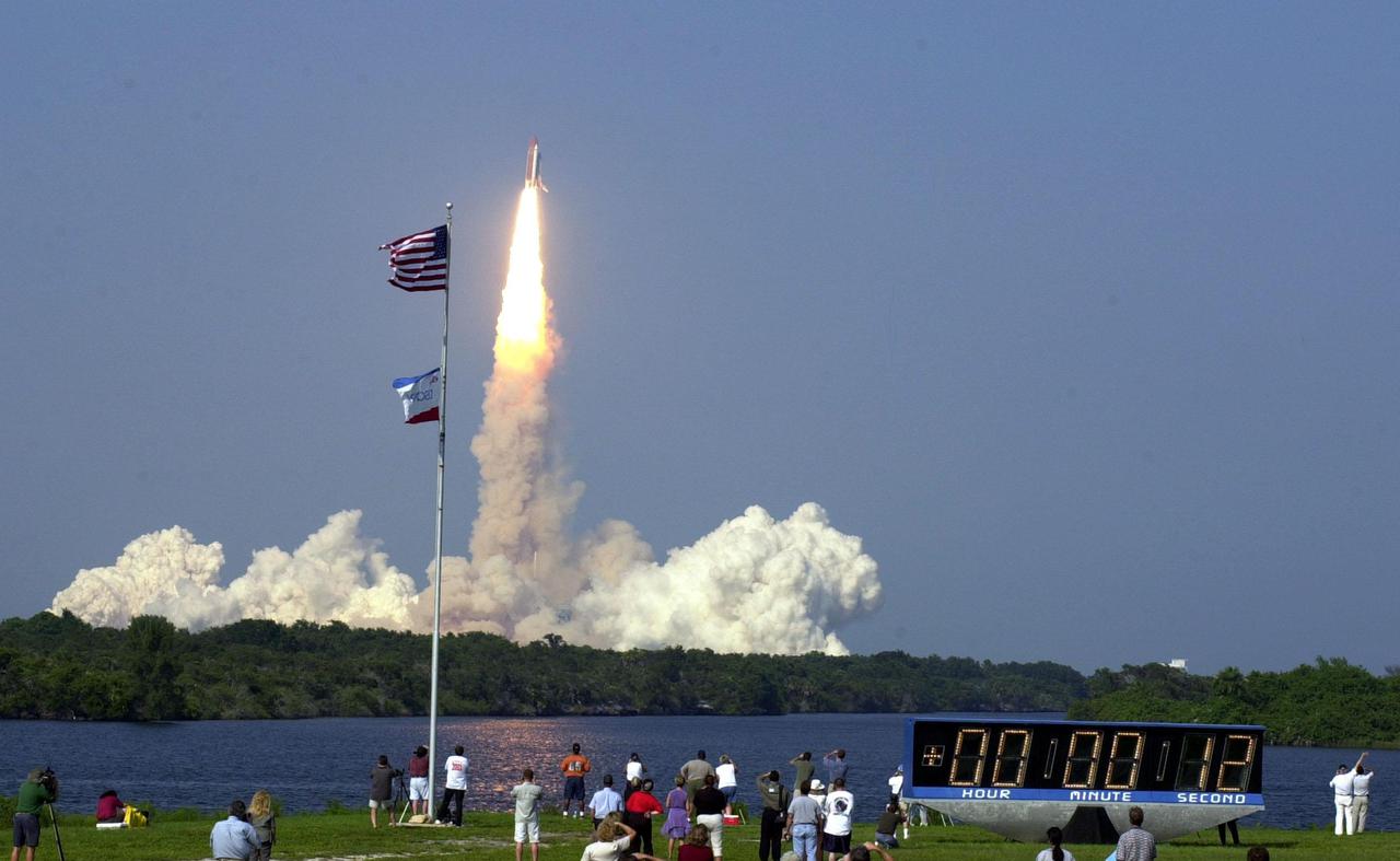 KENNEDY SPACE CENTER, Fla. -- As Space Shuttle Discovery roars into the blue sky over the Space Coast, the brilliant flames of its engines and boosters cast a pink glow in the turn basin. The spectators across the turn basin enjoy the spectacle for on-time liftoff at 5:10:14 p.m. EDT. Besides the Shuttle crew of four, Discovery carries the Expedition Three crew who will replace Expedition Two on the International Space Station. The mission includes the third flight of an Italian-built Multi-Purpose Logistics Module delivering additional scientific racks, equipment and supplies for the Space Station, and two spacewalks. Part of the payload is the Early Ammonia Servicer (EAS) tank, which will be attached to the Station during the spacewalks. The EAS will be installed on the P6 truss, which holds the Station’s giant U.S. solar arrays, batteries and the cooling radiators. The EAS contains spare ammonia for the Station’s cooling system. The three-member Expedition Two crew will be returning to Earth aboard Discovery after a five-month stay on the Station