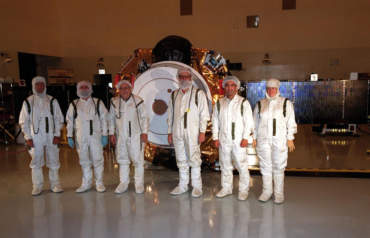 KENNEDY SPACE CENTER, Fla. -- The Genesis project crew stands in front of the spacecraft for a media showing in the Space Assembly and Encapsulation Facility -2. Genesis will capture samples of the ions and elements in the solar wind and return them to Earth for scientists to use to determine the exact composition of the Sun and the solar system's origin. NASA's Genesis project is managed by the Jet Propulsion Laboratory in Pasadena, Calif. Lockheed Martin Astronautics built the Genesis spacecraft for NASA in Denver, Colo. Launch of Genesis aboard a Boeing Delta II rocket is scheduled for July 30 at 12:36 p.m. EDT
