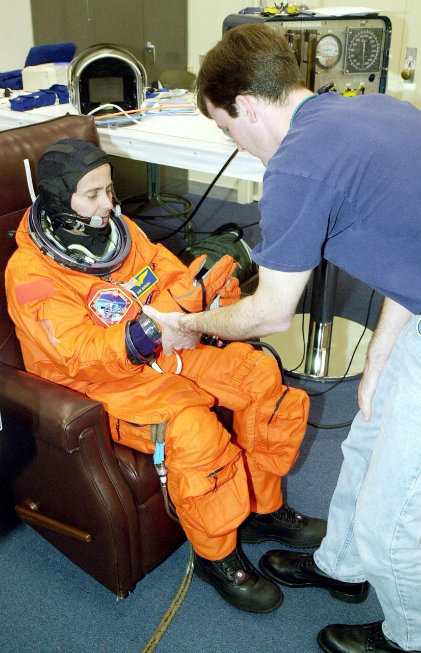 KENNEDY SPACE CENTER, Fla. --  Expedition 4 crew member Daniel W. Bursch gets help with his launch and entry suit as he undergoes suit check before launch on mission STS-108 Nov. 29. Top priorities for the STS-108 (UF-1) mission of Endeavour are rotation of the International Space Station Expedition Three and Expedition Four crews; bringing water, equipment and supplies to the station in the Multi-Purpose Logistics Module Raffaello; and completion of robotics tasks and a spacewalk to install thermal blankets over two pieces of equipment at the bases of the Space Station's solar wings.  Liftoff is scheduled for 7:41 p.m. EST