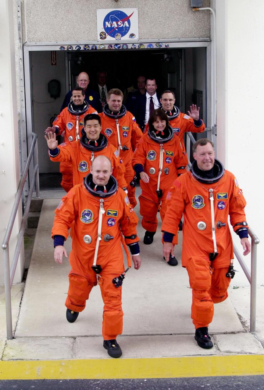 KENNEDY SPACE CENTER, Fla. -   The STS-108 and Expedition 4 crews stride out of the Operations and Checkout Building to the Astrovan bus that will carry them to Space Shuttle Endeavour on Launch Pad 39B.  Beginning with the front row, left to right, are STS-108 Pilot Mark E. Kelly and Commander Dominic L. Gorie; second row, Mission Specialists Daniel M. Tani and Linda A. Godwin; third row, Expedition 4 crew members Daniel W. Bursch, Commander Yuri Onufrienko and Carl E. Walz.   Mission STS-108 is the 12th flight to the International Space Station and the sixth and last flight of 2001.  Top priorities for the 11-day STS-108 (UF-1) mission of Endeavour are rotation of the International Space Station Expedition 3 and Expedition 4 crews; bringing water, equipment and supplies to the station in the Multi-Purpose Logistics Module Raffaello; and the crew's completion of robotics tasks and a spacewalk to install thermal blankets over two pieces of equipment at the bases of the Space Station's solar wings. The three-member Expedition 3 crew will be returning to Earth aboard Endeavour after a five-month stay on the Station.   Launch of Endeavour is scheduled for 5:45 p.m. EST Dec. 4, 2001, from Launch Pad 39B
