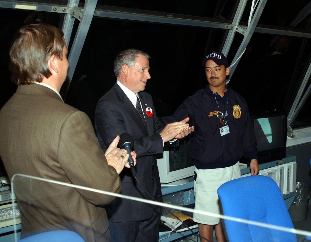 KENNEDY SPACE CENTER, FLA. -- NASA's Acting Administrator Daniel Mulville (center) joins Launch Director Mike Leinbach (left) in recognizing New York Police Department Detective Michael Jermyn in the Firiing Room, Launch Control Center, after watching the launch of Space Shuttle Endeavour on mission STS-108.  Jermyn attended the launch as a guest representing the New York Police and Fire Departments whose members lost their lives in the September 11 attacks.  Endeavour is carrying 6,000 flags that will be given to the families of those who died in the fall of the Twin Towers.  Liftoff of Endeavour occurred at 5:19:28 p.m. EST (22:19.28 GMT).  Endeavour will dock with the International Space Station on Dec. 7. STS-108 is the final Shuttle mission of 2001and the 107th Shuttle flight overall.  It is the 12th flight to the Space Station.  Landing of the orbiter at KSC's Shuttle Landing Facility is targeted for 1:05 p.m. EST (18:05 p.m. GMT) Dec. 16