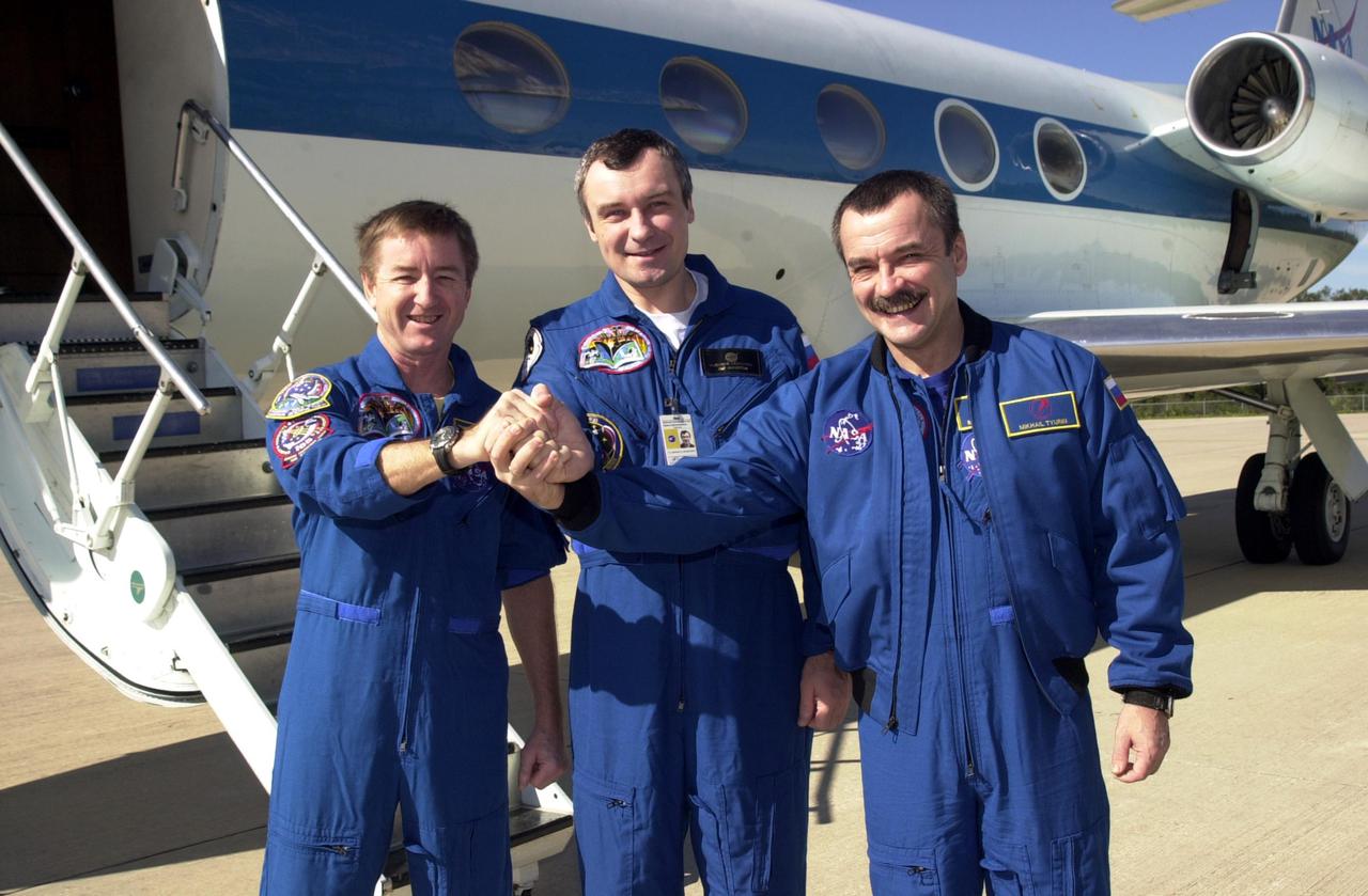 KENNEDY SPACE CENTER, FLA. --   The Expedition Three crew clasp hands in a show of unity before they depart KSC for Houston.  From left to right are Commander Frank Culbertson and cosmonauts Vladimir Dezhurov and Mikhail Tyurin.  The three returned to Earth as passengers aboard the orbiter Endeavour, which landed at KSC at 12:55 p.m. EST (17:55 GMT) Dec. 17, 2001, after completing mission STS-108.  Expedition 3 had spent 129 days on the International Space Station.  The landing is the 57th at KSC in the history of the program   STS-108 was the 12th mission to the Space Station.  This mission was the 107th flight in the Shuttle program and the 17th flight for the orbiter