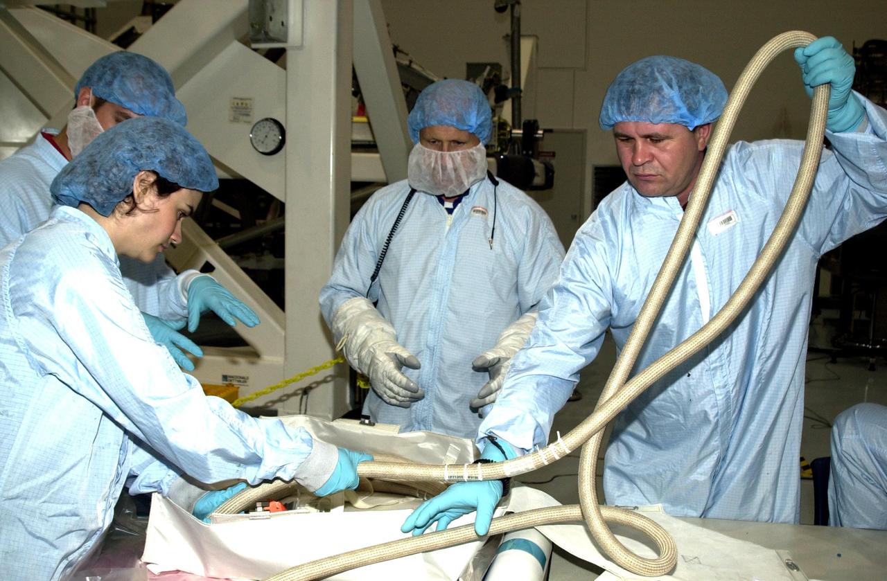 KENNEDY SPACE CENTER, FLA. -- Members of the Expedition 6 crew practice using equipment they will be handling during their residency on the International Space Station. In the center of the photo is Commander Ken Bowersox; holding the flexible hose is crew member Nikolai Budarin. Donald Thomas is the third member of the crew. Expedition 6 is attached to mission STS-113, scheduled to launch in September 2002.