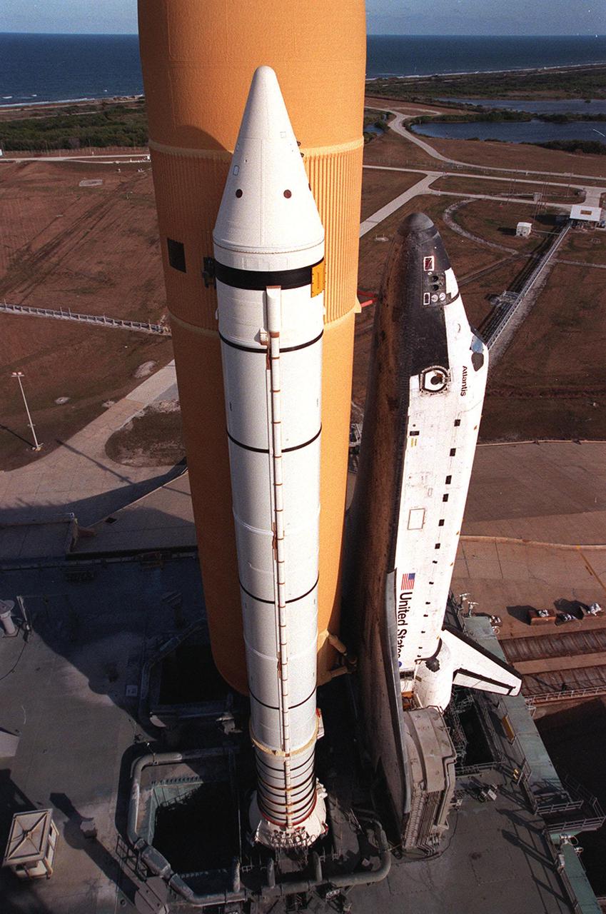KENNEDY SPACE CENTER, Fla. -- Resting atop the Mobile Launcher Platform, Space Shuttle Atlantis is viewed from a high level on the Fixed Service Structure. Seen is one of its solid rocket boosters and the external tank. Next to the wing of the orbiter is one of two tail service masts, which support the fluid, gas and electrical requirements of the orbiter’s liquid oxygen and liquid hydrogen aft T-0 umbilicals. On the horizon is the Atlantic Ocean. Atlantis will fly on mission STS-98, the seventh construction flight to the International Space Station, carrying the U.S. Laboratory, named Destiny. The lab has five system racks already installed inside the module. After delivery of electronics in the lab, electrically powered attitude control for Control Moment Gyroscopes will be activated. Atlantis is scheduled for launch no earlier than Jan. 19, 2001, with a crew of five