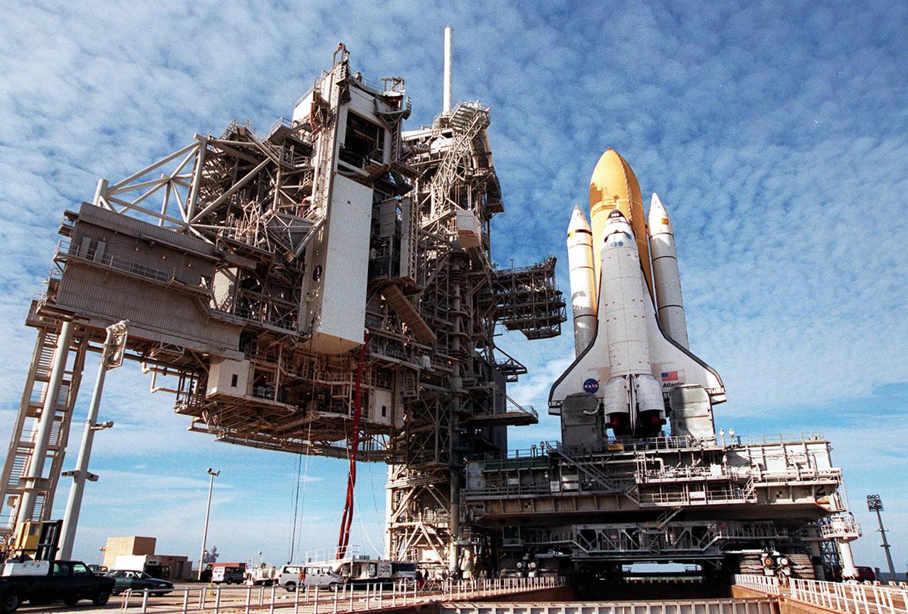 KENNEDY SPACE CENTER, Fla. -- Space Shuttle Atlantis reaches its destination, Launch Pad 39A, for liftoff no earlier than Jan. 19 on mission STS-98. To its immediate left is the Fixed Service Structure, with its 80-foot-tall white lighting mast on top. Further to the left is the Rotating Service Structure, where the white payload canister is being lifted to the Payload Changeout Room. The payload for the mission is the U.S. Lab Destiny, a key element in the construction of the International Space Station. The lab has five system racks for experiments already installed inside the module. After delivery of electronics in the lab, electrically powered attitude control for Control Moment Gyroscopes will be activated