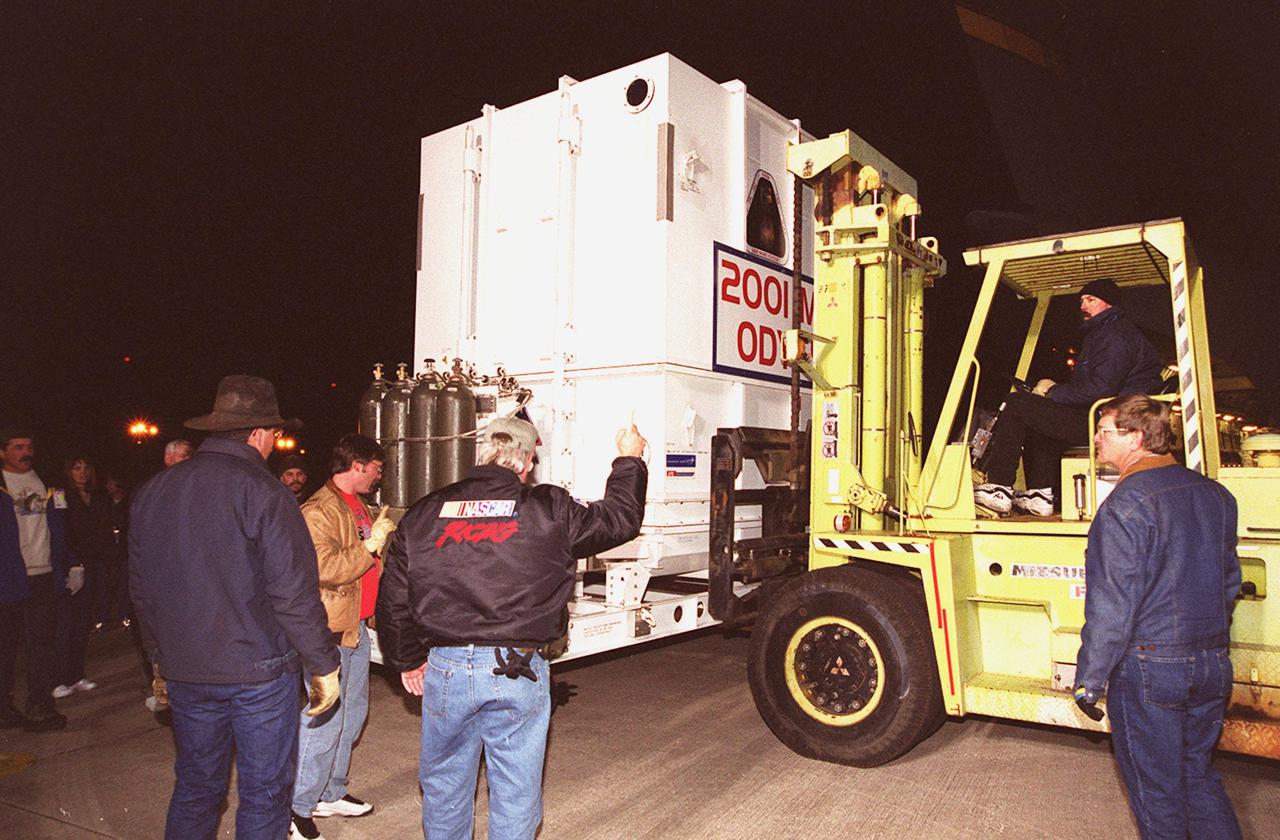 A forklift carries the crated Mars Odyssey spacecraft from the Air Force C-17 cargo airplane that brought it from Denver, Colo.., location of the Lockheed Martin plant where the spacecraft was built. The crate will placed on a transport trailer to take it from KSC’s Shuttle Landing Facility to the Spacecraft Assembly and Encapsulation Facility 2 (SAEF-2) located in the KSC Industrial Area. In the SAEF it will undergo final assembly and checkout. This includes installation of two of the three science instruments, integration of the three-panel solar array, and a spacecraft functional test. It will be fueled and then mated to an upper stage booster, the final activities before going to the launch pad. Launch is planned for April 7, 2001 the first day of a 21-day planetary window. Mars Odyssey will be inserted into an interplanetary trajectory by a Boeing Delta II launch vehicle from Pad A at Complex 17 at the Cape Canaveral Air Force Station, Fla. The spacecraft will arrive at Mars on Oct. 20, 2001, for insertion into an initial elliptical capture orbit. Its final operational altitude will be a 250-mile-high, Sun-synchronous polar orbit. Mars Odyssey will spend two years mapping the planet's surface and measuring its environment