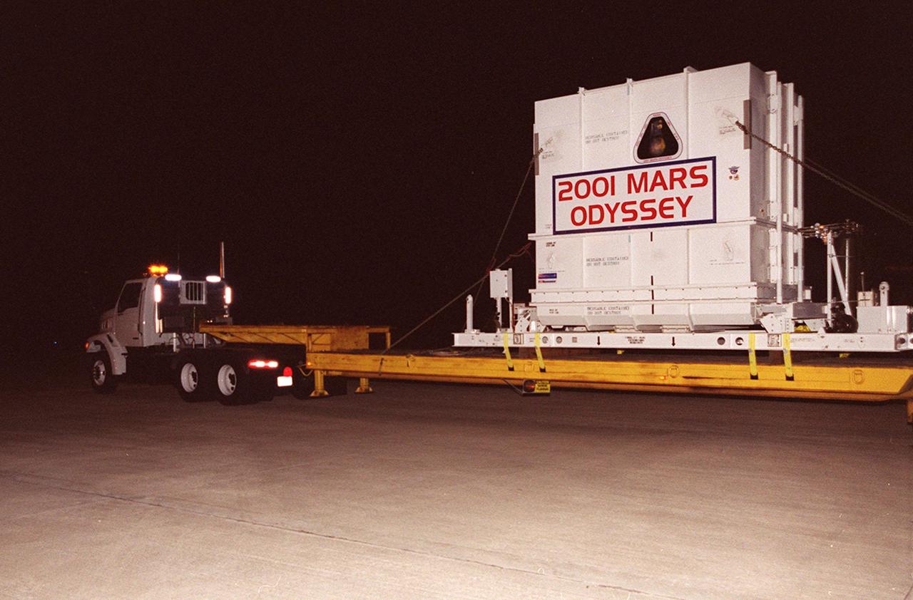The 2001 Mars Odyssey spacecraft leaves the KSC Shuttle Landing Facility on the bed of a transport trailer. The spacecraft is being moved to the Spacecraft Assembly and Encapsulation Facility 2 (SAEF-2) located in the KSC Industrial Area. The spacecraft arrived at the SLF aboard an Air Force C-17 cargo airplane that brought it from Denver, Colo.., location of the Lockheed Martin plant where the spacecraft was built. In the SAEF, Odyssey will undergo final assembly and checkout. This includes installation of two of the three science instruments, integration of the three-panel solar array, and a spacecraft functional test. It will be fueled and then mated to an upper stage booster, the final activities before going to the launch pad. Launch is planned for April 7, 2001 the first day of a 21-day planetary window. Mars Odyssey will be inserted into an interplanetary trajectory by a Boeing Delta II launch vehicle from Pad A at Complex 17 at the Cape Canaveral Air Force Station, Fla. The spacecraft will arrive at Mars on Oct. 20, 2001, for insertion into an initial elliptical capture orbit. Its final operational altitude will be a 250-mile-high, Sun-synchronous polar orbit. Mars Odyssey will spend two years mapping the planet's surface and measuring its environment