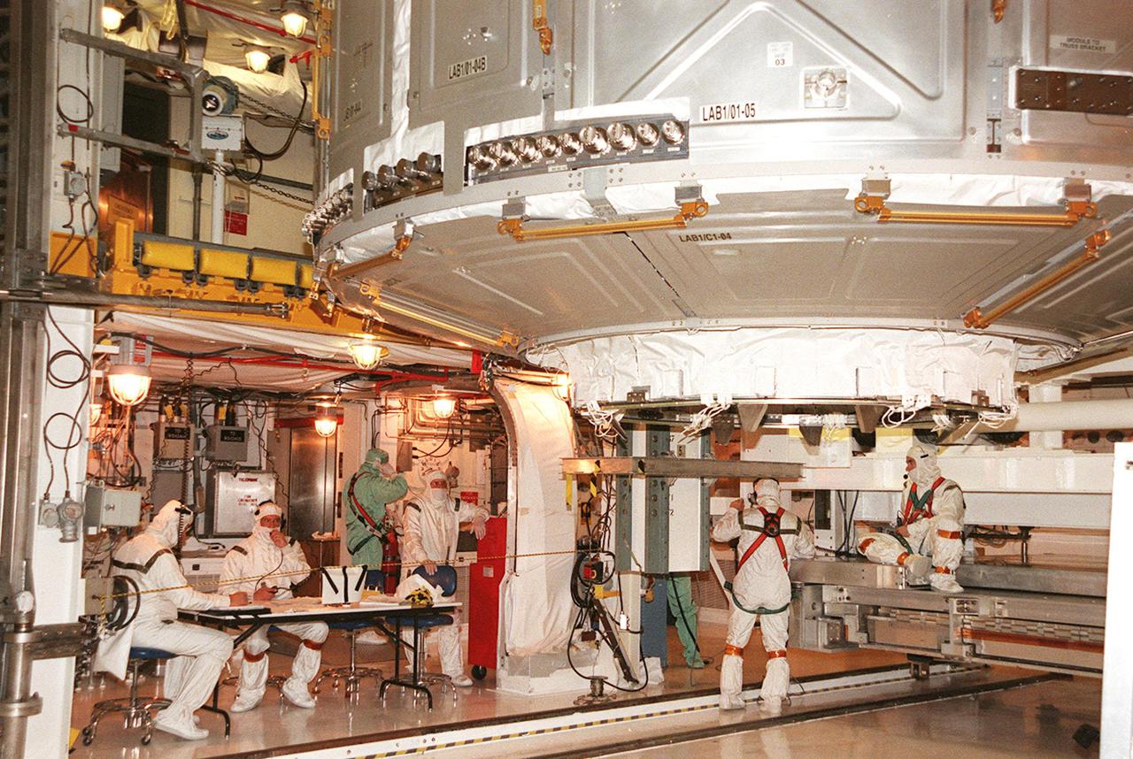 KENNEDY SPACE CENTER, FLA. -- Technicians in the Payload Changeout Room oversee the transfer of the U.S. Lab Destiny to the orbiter’s payload bay. The PCR is the enclosed, environmentally controlled portion of the rotating service structure that supports payload delivery at the launch pad and vertical installation in the orbiter payload bay. Destiny, a key element in the construction of the International Space Station is designed for space science experiments and already has five system racks installed inside. STS-98 is the seventh construction flight to the ISS. Launch of STS-98 is scheduled for Jan. 19 at 2:11 a.m. EST