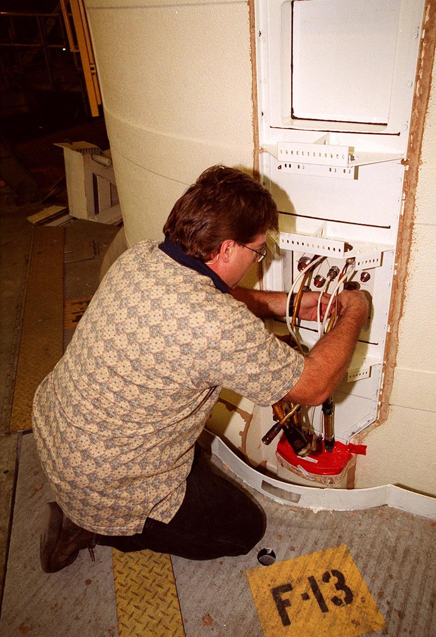 KENNEDY SPACE CENTER, FLA. -- In the Vehicle Assembly Building, Richard Bruns, a United Space Alliance SRB technician, pulls cables out of the solid rocket booster system tunnel. The SRB is part of Space Shuttle Atlantis, rolled back from Launch Pad 39A in order to conduct tests on the cables. A prior extensive evaluation of NASA’s SRB cable inventory on the shelf revealed conductor damage in four (of about 200) cables. Shuttle managers decided to prove the integrity of the system tunnel cables already on Atlantis before launching. Workers are conducting inspections, making continuity checks and conducting X-ray analysis on the cables. The launch has been rescheduled no earlier than Feb. 6. <br