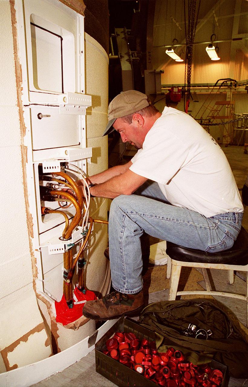 KENNEDY SPACE CENTER, FLA. -- In the Vehicle Assembly Building, United Space Alliance SRB technician Frank Meyer pulls cables out of the solid rocket booster system tunnel. Cable end covers are in a box near his feet. The SRB is part of Space Shuttle Atlantis, rolled back from Launch Pad 39A in order to conduct tests on the cables. A prior extensive evaluation of NASA’s SRB cable inventory on the shelf revealed conductor damage in four (of about 200) cables. Shuttle managers decided to prove the integrity of the system tunnel cables already on Atlantis before launching. Workers are conducting inspections, making continuity checks and conducting X-ray analysis on the cables. The launch has been rescheduled no earlier than Feb. 6. <br