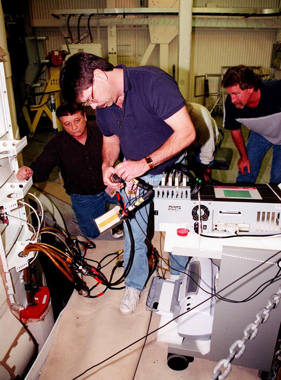 KENNEDY SPACE CENTER, FLA. -- NASA and United Space Alliance SRB technicians hook up solid rocket booster cables to a Cirris Signature Touch 1 cable tester. From left are Loren Atkinson and Steve Swichkow, with NASA, and Jeff Suter, with USA. The SRB is part of Space Shuttle Atlantis, rolled back from Launch Pad 39A in order to conduct tests on the cables. A prior extensive evaluation of NASA’s SRB cable inventory on the shelf revealed conductor damage in four (of about 200) cables. Shuttle managers decided to prove the integrity of the system tunnel cables already on Atlantis before launching. Workers are conducting inspections, making continuity checks and conducting X-ray analysis on the cables. The launch has been rescheduled no earlier than Feb. 6. <br
