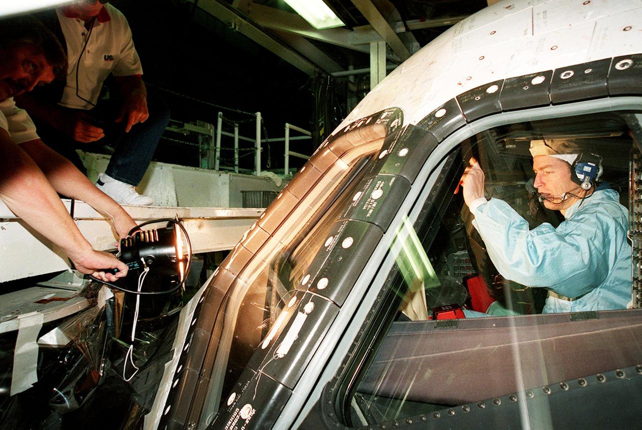 In the Orbiter Processing Facility bay 1, STS-102 Commander James D. Wetherbee checks out the window of Discovery from the inside while workers (left) check the outside.; The mission crew is at KSC for Crew Equipment Interface Test activities. STS-102 is the 8th construction flight to the International Space Station and will carry the Multi-Purpose Logistics Module Leonardo. STS-102 is scheduled for launch March 1, 2001. On that flight, Leonardo will be filled with equipment and supplies to outfit the U.S. laboratory module Destiny. The mission will also be carrying the Expedition Two crew to the Space Station, replacing the Expedition One crew who will return on Shuttle Discovery