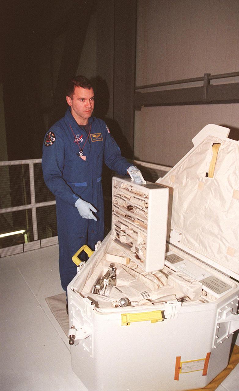 In the Orbiter Processing Facility bay 1, STS-102 Mission Specialist Paul D. Richards looks over tools in the tool caddy that is carried on launches. The mission crew is at KSC for Crew Equipment Interface Test activities