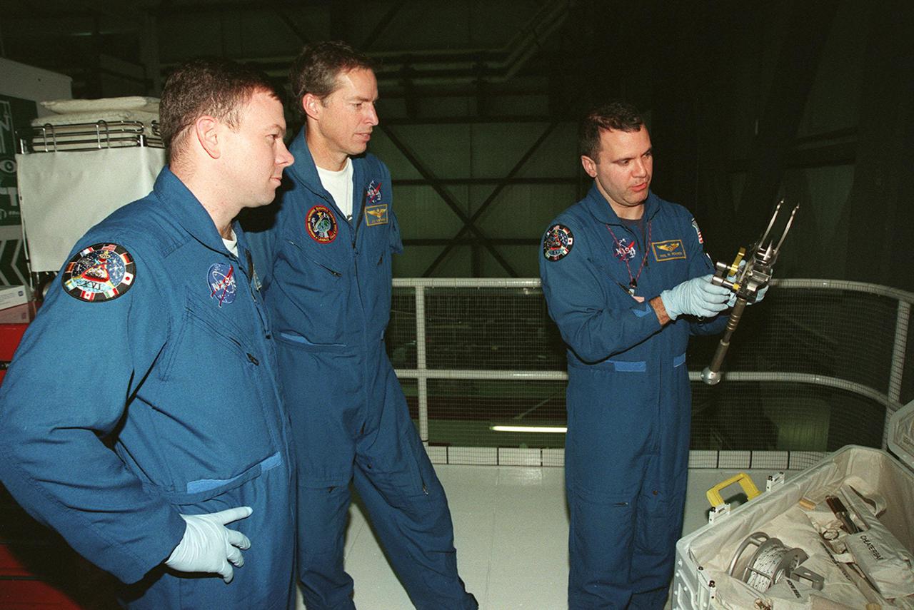 While STS-102 Pilot James W. Kelly and Commander James D. Wetherbee watch, Mission Specialist Paul W. Richards checks out a piece of equipment from the tool caddy below. The mission crew is at KSC for Crew Equipment Interface Test activities. STS-102 is the 8th construction flight to the International Space Station and will carry the Multi-Purpose Logistics Module Leonardo. STS-102 is scheduled for launch March 1, 2001. On that flight, Leonardo will be filled with equipment and supplies to outfit the U.S. laboratory module Destiny. The mission will also be carrying the Expedition Two crew to the Space Station, replacing the Expedition One crew who will return on Shuttle Discovery