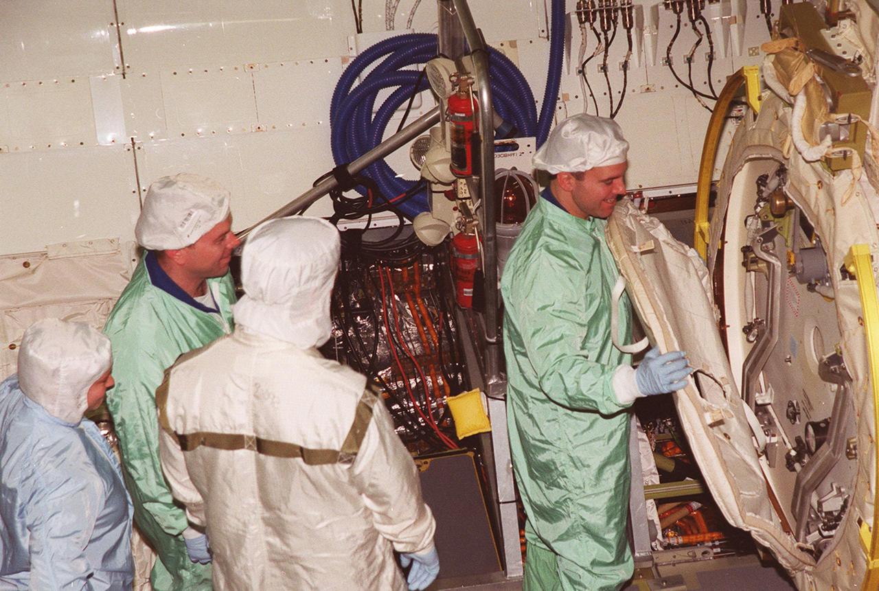 In the Orbiter Processing Facility bay 1, STS-102 Pilot James W. Kelly (left) looks on while Mission Specialist Paul W. Richards checks out equipment in Discovery’s payload bay. The crew is at KSC for Crew Equipment Interface Test activities. STS-102 is the 8th construction flight to the International Space Station and will carry the Multi-Purpose Logistics Module Leonardo. STS-102 is scheduled for launch March 1, 2001. On that flight, Leonardo will be filled with equipment and supplies to outfit the U.S. laboratory module Destiny. The mission will also be carrying the Expedition Two crew to the Space Station, replacing the Expedition One crew who will return on Shuttle Discovery
