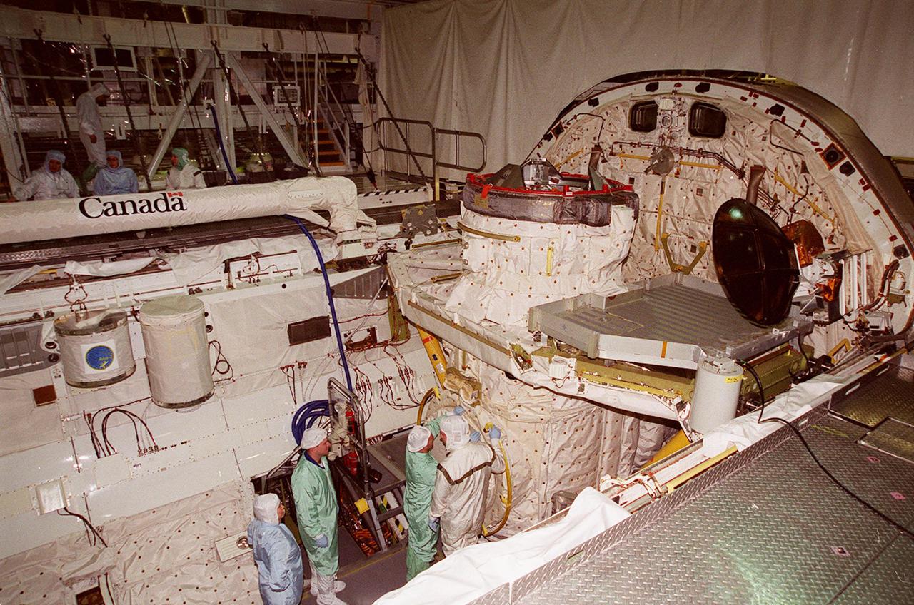 In the Orbiter Processing Facility bay 1, STS-102 Mission Specialist Paul W. Richards (left) looks on while Pilot James W. Kelly; checks out equipment in Discovery’s payload bay. Above them (left) are two GetAway Special canisters that contain experiments for the mission. Above them is the Canadian robotic arm, used to manipulate modules during the construction of the International Space Station. The crew is at KSC for Crew Equipment Interface Test activities. STS-102 is the 8th construction flight to the Space Station and will carry the Multi-Purpose Logistics Module Leonardo. STS-102 is scheduled for launch March 1, 2001. On that flight, Leonardo will be filled with equipment and supplies to outfit the U.S. laboratory module Destiny. The mission will also be carrying the Expedition Two crew to the Space Station, replacing the Expedition One crew who will return on Shuttle Discovery