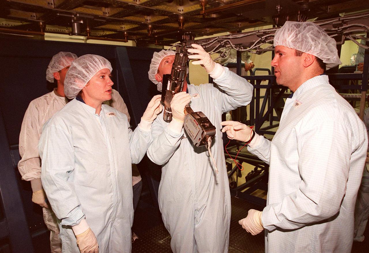 KENNEDY SPACE CENTER, FLA. -- At SPACEHAB, members of the STS-102 crew get acquainted with tools and equipment they will be using on their mission. Mission Specialist Andrew S.W. Thomas (center) practices using one of the tools while Mission Specialist Paul W. Richards (right) and Expedition Two’s Susan Helms look on. They and other crew members are at SPACEHAB to get acquainted with tools and equipment they will be using on their mission. STS-102 is the 8th construction flight to the International Space Station and will carry the Multi-Purpose Logistics Module Leonardo. On that flight, Leonardo will be filled with equipment and supplies to outfit the U.S. laboratory module Destiny. The mission will also be carrying the Expedition Two crew to the Space Station, replacing the Expedition One crew who will return on Shuttle Discovery. STS-102 is scheduled for launch March 8, 2001