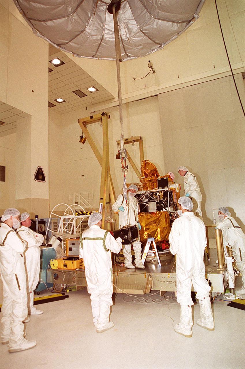 In the Spacecraft Assembly and Encapsulation Facility 2, an overhead crane lifts and moves the Thermal Emission Imaging System (THEMIS) toward the 2001 Mars Odyssey Orbiter. THEMIS will map the mineralogy and morphology of the Martian surface using a high-resolution camera and a thermal infrared imaging spectrometer. The orbiter will carry three science instruments: THEMIS, the Gamma Ray Spectrometer (GRS), and the Mars Radiation Environment Experiment (MARIE). The GRS will achieve global mapping of the elemental composition of the surface and determine the abundance of hydrogen in the shallow subsurface. The MARIE will characterize aspects of the near-space radiation environment with regards to the radiation-related risk to human explorers. The Mars Odyssey Orbiter is scheduled for launch on April 7, 2001, aboard a Delta 7925 rocket from Launch Pad 17-A, Cape Canaveral Air Force Station