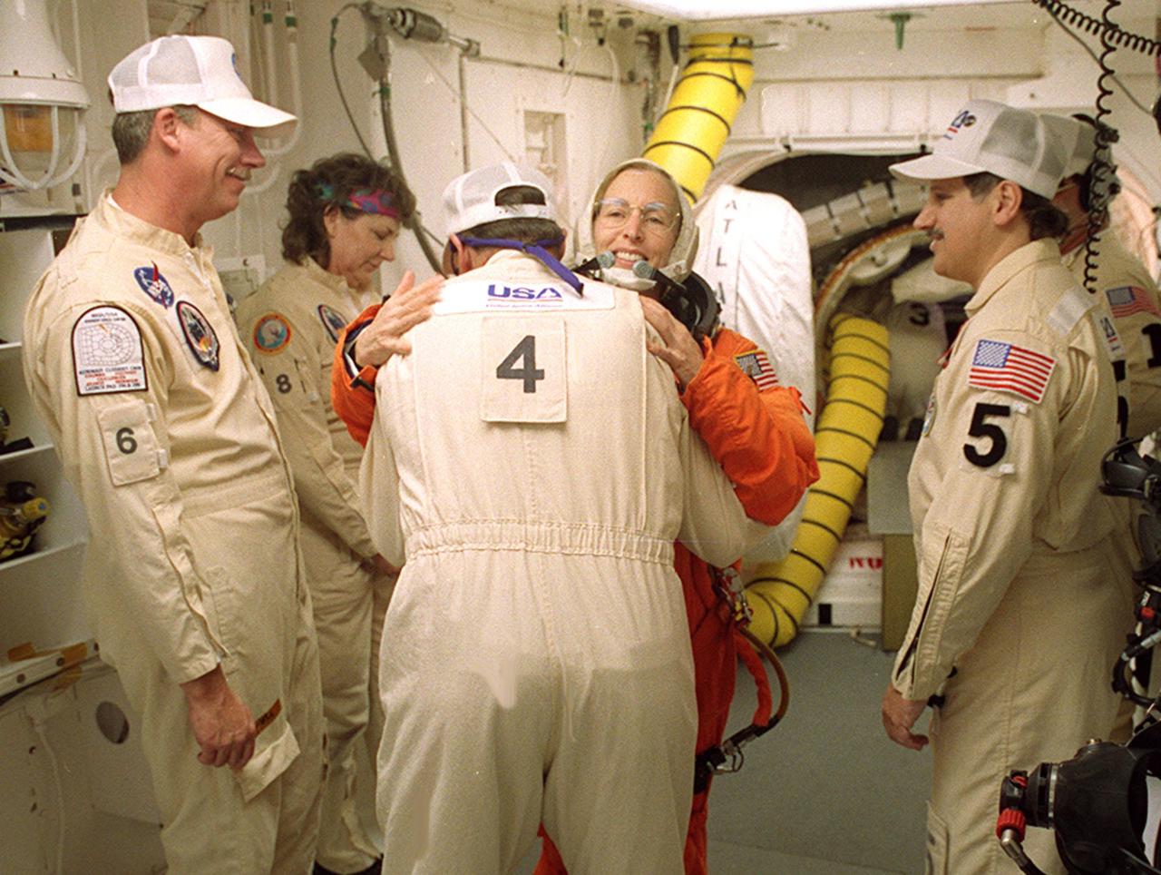 In the White Room before launch, STS-98 Mission Specialist Marsha Ivins gets a hug from a closeout crew member before she enters Space Shuttle Atlantis. The White Room is an environmentally controlled room at the end of the Orbiter Access Arm. Atlantis is carrying the U.S. Laboratory Destiny, a key module in the growth of the Space Station. Destiny will be attached to the Unity node on the Space Station using the Shuttle’s robotic arm. Three spacewalks are required to complete the planned construction work during the 11-day mission. This mission marks the seventh Shuttle flight to the Space Station, the 23rd flight of Atlantis and the 102nd flight overall in NASA’s Space Shuttle program. The planned landing is at KSC Feb. 18 about 1 p.m