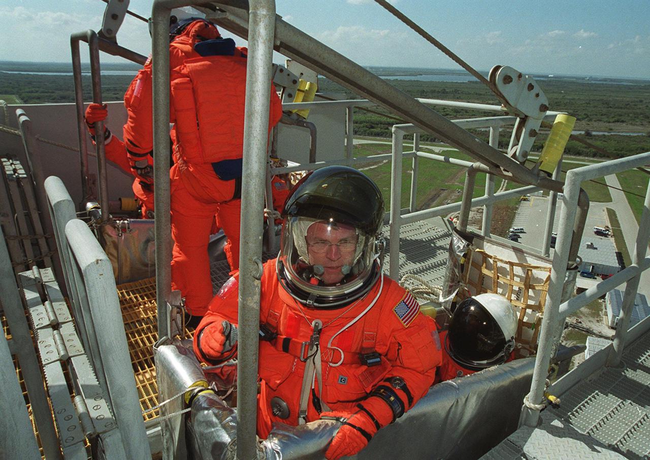 STS-102 Mission Specialists Andrew Thomas (front, left) and Paul Richards take their seats in the slidewire basket, used for emergency egress from the orbiter and pad. Behind them, other crew members climb into their basket. The crew is at KSC for Terminal Countdown Demonstration Test activities, which include the emergency training and a simulated launch countdown.; STS-102 is the eighth construction flight to the International Space Station, with Space Shuttle Discovery carrying the Multi-Purpose Logistics Module Leonardo. In addition, the Expedition Two crew will be on the mission, to replace Expedition One, who will return to Earth with Discovery. Launch on mission STS-102 is scheduled for March 8