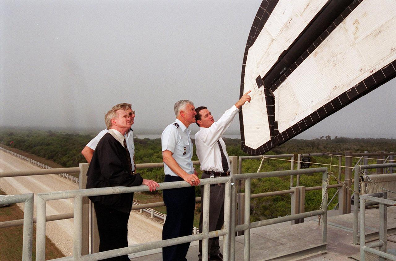 While on the crawler-transporter at Launch Pad 39B, Dave King, director of Shuttle Processing, points to tiles on the tail of Space Shuttle Discovery as (left to right) Center Director Roy Bridges, Brig. Gen. Donald Pettit and Gen. Ralph Everhart look on. Gen. Pettit is Commander of the 45th Space Wing, Cape Canaveral. Gen. Everhart is Commander of Space Command. Discovery rolled out to the pad earlier in the day