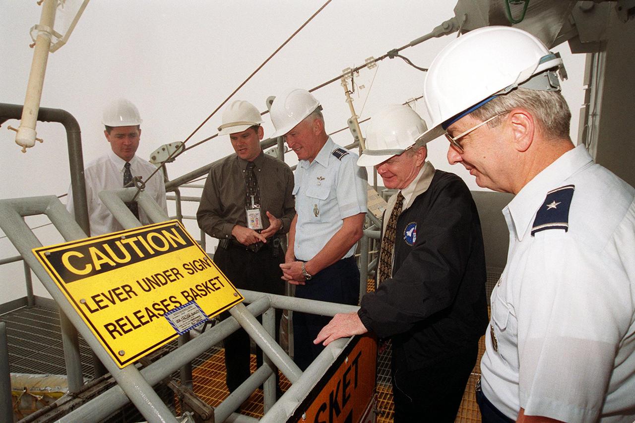 On the Fixed Service Structure on Launch Pad 39B, this distinguished group look at the emergency escape equipment that could be used by astronauts and workers if needed. Gathered around the slidewire basket are Dave King, director of Shuttle Processing; Dave Rainer; Gen. Ralph Everhart, Commander, Space Command; Center Director Roy Bridges; and Brig. Gen. Donald Pettit, Commander of the 45th Space Wing, Cape Canaveral