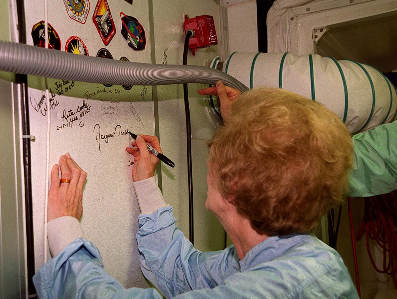 During a tour of KSC, Lady Margaret Thatcher, former Prime Minister of Britain, signs a wall in the Orbiter Processing Facility. She has just completed an inside tour of the orbiter Endeavour. The orbiter, which is in OPF bay 2, is flying on mission STS-100, the ninth construction flight to the International Space Station