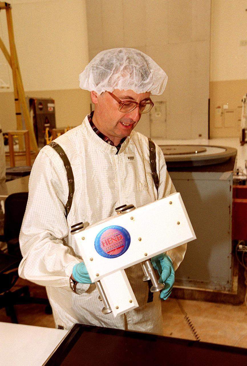 In the Spacecraft Assembly and Encapsulation Facility 2, a Russian scientist (SAEF-2) looks over the High Energy Neutron Detector (HEND), part of the Gamma Ray Spectrometer (GRS), after its removal from the 2001 Mars Odyssey Orbiter. The HEND was built by Russia’s Space Research Institute (IKI). The GRS will achieve global mapping of the elemental composition of the surface and determine the abundance of hydrogen in the shallow subsurface. The orbiter will carry two other science instruments: THEMIS and the Mars Radiation Environment Experiment (MARIE). THEMIS will map the mineralogy and morphology of the Martian surface using a high-resolution camera and a thermal infrared imaging spectrometer. The MARIE will characterize aspects of the near-space radiation environment with regards to the radiation-related risk to human explorers. The Mars Odyssey Orbiter is scheduled for launch April 7, 2001, aboard a Delta 7925 rocket from Launch Pad 17-A, Cape Canaveral Air Force Station