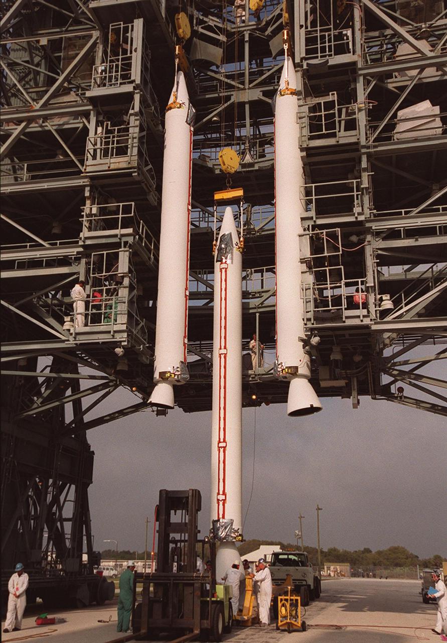 A third solid rocket booster is lifted up the gantry between two others on Launch Pad 17-A, Cape Canaveral Air Force Station. They will be mated with a Delta 7925 rocket for launch April 7, 2001. The rocket will carry the 2001 Mars Odyssey Orbiter, containing three science instruments: THEMIS, the Gamma Ray Spectrometer (GRS), and the Mars Radiation Environment Experiment (MARIE). THEMIS will map the mineralogy and morphology of the Martian surface using a high-resolution camera and a thermal infrared imaging spectrometer. The GRS will achieve global mapping of the elemental composition of the surface and determine the abundance of hydrogen in the shallow subsurface. The MARIE will characterize aspects of the near-space radiation environment with regards to the radiation-related risk to human explorers