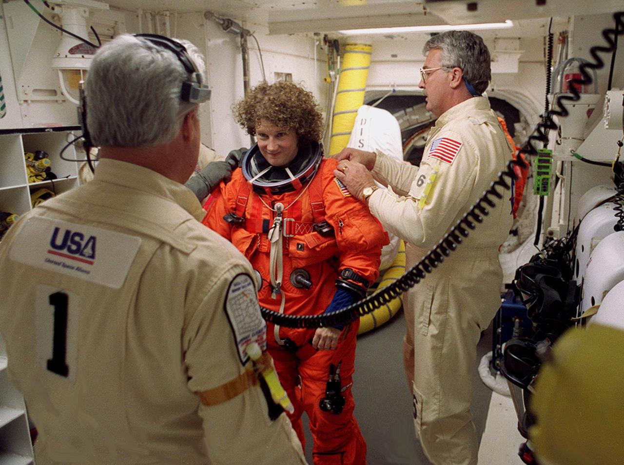 Technicians in the White Room, Launch Pad 39B, help STS-102 Mission Specialist Susan Helms with her launch and entry suit before she enters Space Shuttle Discovery. The mission is Helms’ fifth Shuttle flight. Helms is also part of the Expedition Two crew flying on the mission to replace the Expedition One crew on the Station. Discovery is carrying the Multi-Purpose Logistics Module Leonardo on the eighth construction flight to the International Space Station. The primary delivery system used to resupply and return Station cargo requiring a pressurized environment, Leonardo will deliver up to 10 tons of laboratory racks filled with equipment, experiments and supplies for outfitting the newly installed U.S. Laboratory Destiny. Discovery is set to launch March 8 at 6:42 a.m. EST. The 12-day mission is expected to end with a landing at KSC on March 20