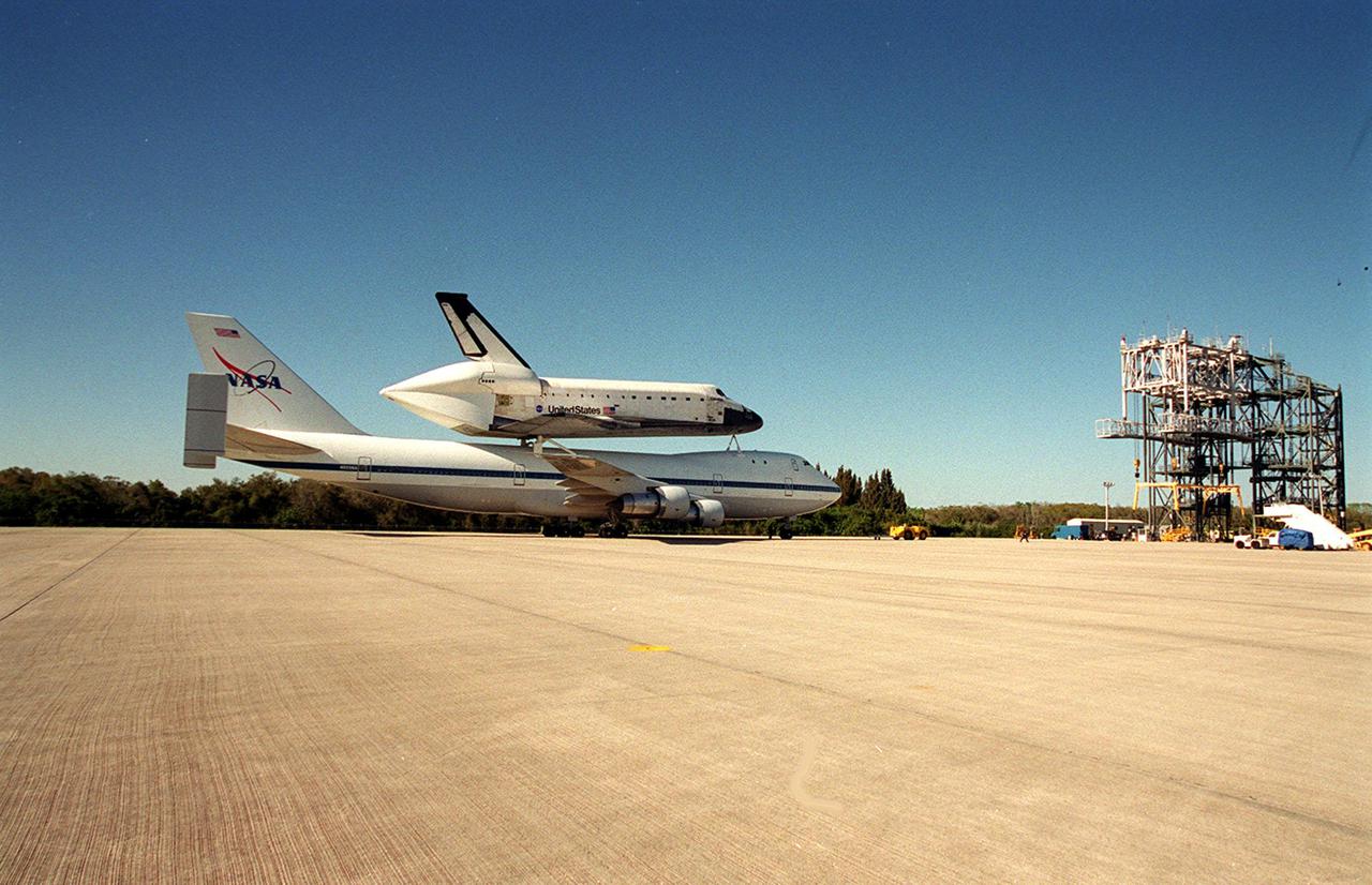 The Shuttle Carrier Aircraft with orbiter Columbia riding piggyback taxis toward the mate_demate device at the KSC Shuttle Landing Facility. At the MDD, Columbia will be lifted off the SCA and towed to the Orbiter Processing Facility bay 1. Columbia’s ferry flight began in California March 1. Unfavorable weather conditions kept it on the ground at Dyess AFB, Texas, until it could return to Florida. It landed temporarily at the CCAFS Skid Strip until Atlantis, which had already landed at the SLF, could be transferred. Columbia is returning from a 17-month-long modification and refurbishment process as part of a routine maintenance plan. The orbiter will next fly on mission STS-107, scheduled Oct. 25