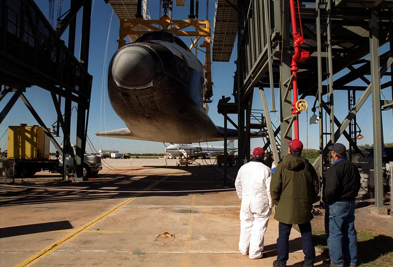 Orbiter Atlantis is suspended by an overhead crane in the mate_demate device at KSC’s Shuttle Landing Facility. It was removed from the back of the Shuttle Carrier Aircraft in the background. Atlantis just returned from California atop the SCA after its Feb. 19 landing at Edwards Air Force Base concluding mission STS-98. The ferry flight began March 1; unfavorable weather conditions kept it on the ground at Altus AFB, Okla., until it could return to Florida. Atlantis will be transported to the Orbiter Processing Facility to prepare it for mission STS-104, the 10th construction flight to the International Space Station, scheduled to launch June 8