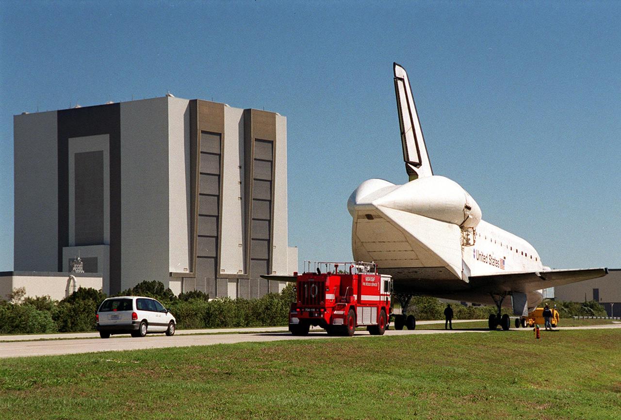 Towed from the Shuttle Landing Facility, Atlantis heads for the Orbiter Processing Facility (far right), accompanied by a KSC_CCAFS rescue vehicle. In view is the tail cone that orbiters use when being carried piggyback on ferry flights atop a Shuttle Carrier Aircraft. The tail cone protects the aft engine area and provides a more efficient aeronautical dimension during flight. Atlantis returned from California atop a Shuttle Carrier Aircraft after its Feb. 19 landing at Edwards Air Force Base, concluding mission STS-98. The ferry flight began March 1; unfavorable weather conditions kept it on the ground at Altus AFB, Okla., until it could return to Florida. In the Orbiter Processing Facility, Atlantis will be prepared for mission STS-104, the 10th construction flight to the International Space Station, scheduled to launch June 8