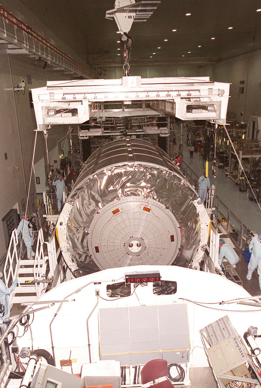 KENNEDY SPACE CENTER, FLA. -- In the Space Station Processing Facility, workers watch while an overhead crane lowers the Multi-Purpose Logistics Module Raffaello onto a weight and balance stand (foreground). Raffaello is the second MPLM built by the Italian Space Agency, and serves as a reusable logistics carrier and primary delivery system used to resupply and return station cargo requiring a pressurized environment. Weighing nearly 4.5 tons, the Raffaello measures 21 feet long and 15 feet in diameter. The MPLM will fly on mission STS-100, scheduled to launch aboard Space Shuttle Endeavour on April 19