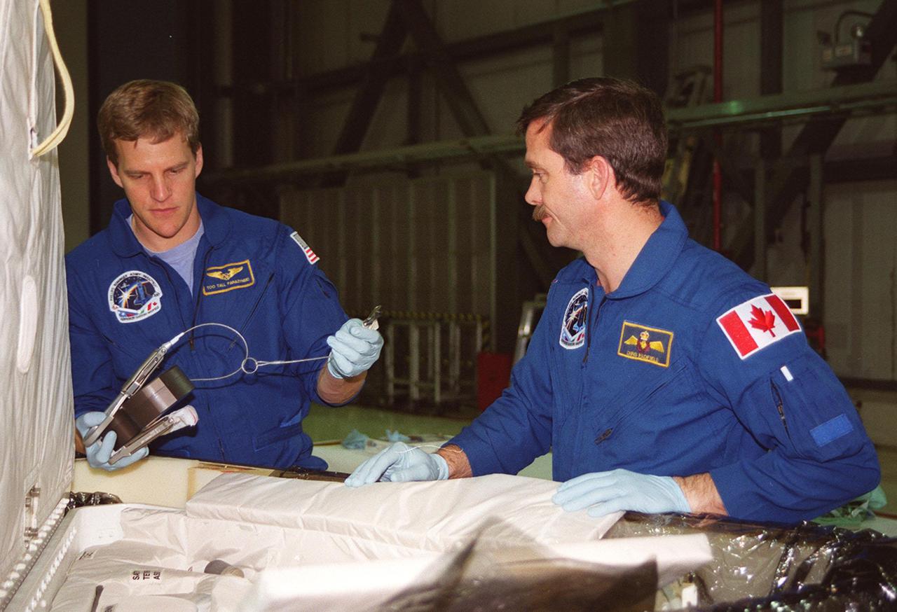 STS-100 Mission Specialists Scott Parazynski (left) and Chris Hadfield (right), who is with the Canadian Space Agency, look over equipment that will be used during their mission. They are taking part in a Crew Equipment Interface Test (CEIT) at KSC, along with other crew members Commander Kent V. Rominger, Pilot Jeffrey S. Ashby and Mission Specialists John L. Phillips, Umberto Guidoni, who is with the European Space Agency, and Yuri Lonchakov, who is with the Russian Aviation and Space Agency. The orbiter is also carrying the Multi-Purpose Logistics Module Raffaello to the International Space Station. Raffaello carries six system racks and two storage racks for the U.S. Lab. Launch of mission STS-100 is scheduled for April 19 at 2:41 p.m. EDT from Launch Pad 39A