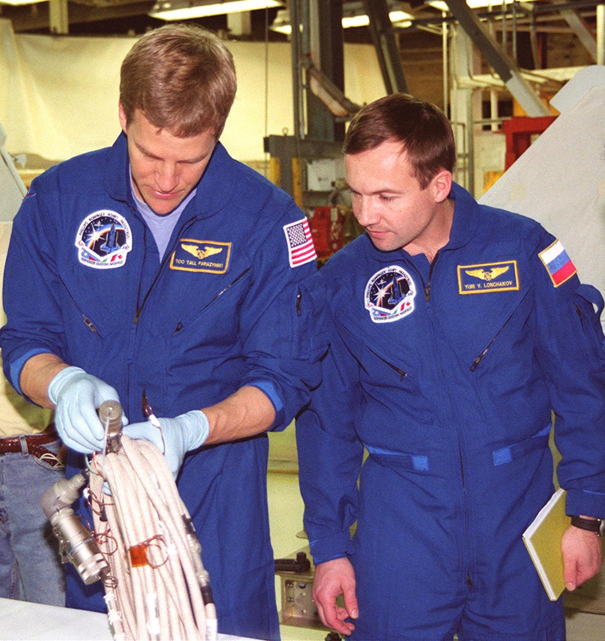 STS-100 Mission Specialists Scott Parazynski (left) and Yuri Lonchakov, who is with the Russian Aviation and Space Agency, look over equipment that will be used during their mission. They are taking part in a Crew Equipment Interface Test (CEIT) at KSC, along with other crew members Commander Kent V. Rominger, Pilot Jeffrey S. Ashby and Mission Specialists Chris Hadfield, who is with the Canadian Space Agency, John L. Phillips and Umberto Guidoni, who is with the European Space Agency. The orbiter is also carrying the Multi-Purpose Logistics Module Raffaello to the International Space Station. Raffaello carries six system racks and two storage racks for the U.S. Lab. Launch of mission STS-100 is scheduled for April 19 at 2:41 p.m. EDT from Launch Pad 39A